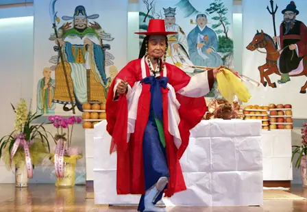 Mudang performing a ritual placating the angry spirits of the dead — A mudang (Korean female shaman) holding a ritual ( gut ) to placate the angry spirits of the dead preventing t…